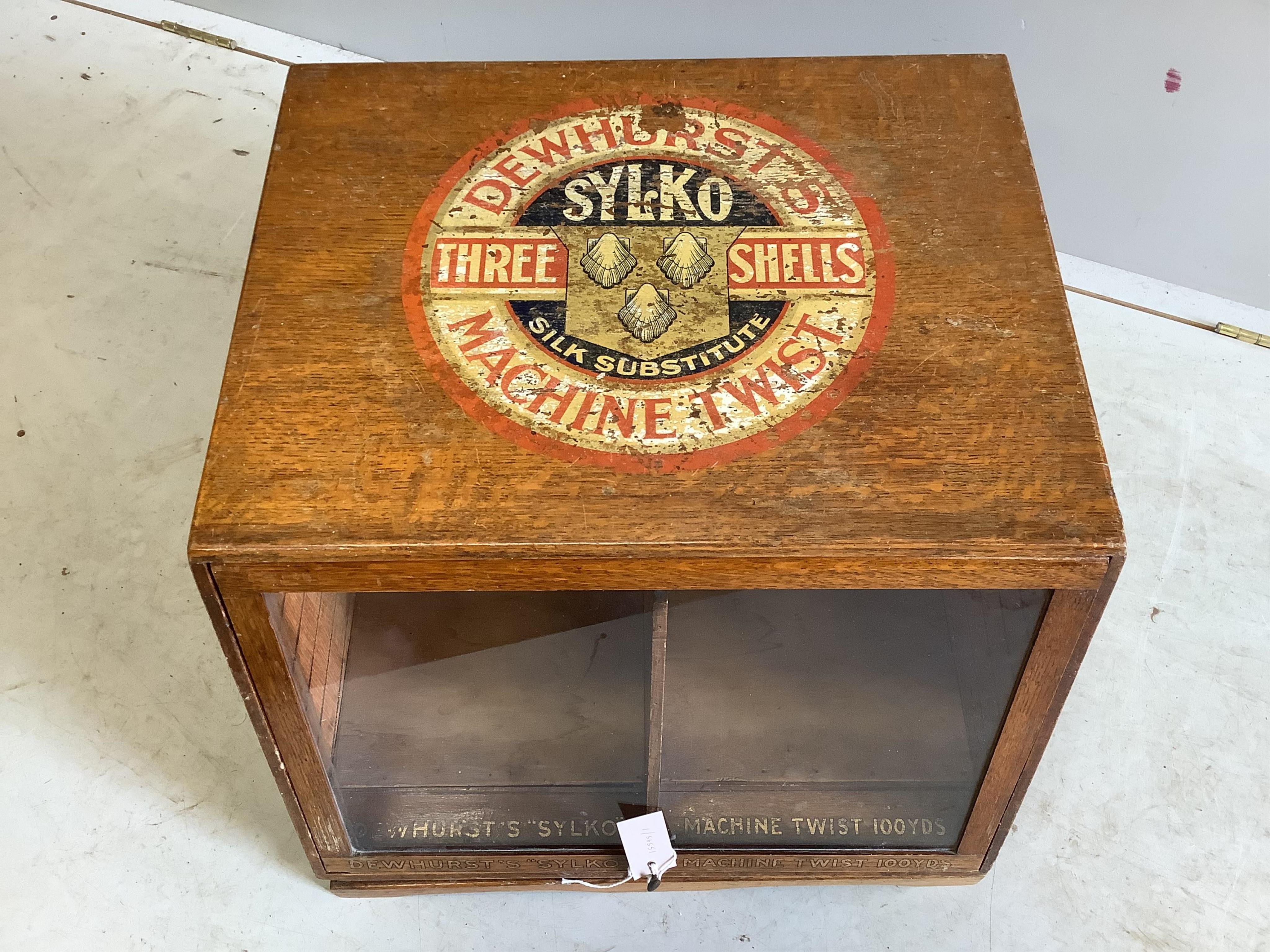 An early 20th century oak counter top display case, “Dewhurst’s Sylko Three Shells Machine Twist”, on swivel base, width 54cm, depth 52cm, height 42cm. Condition - fair